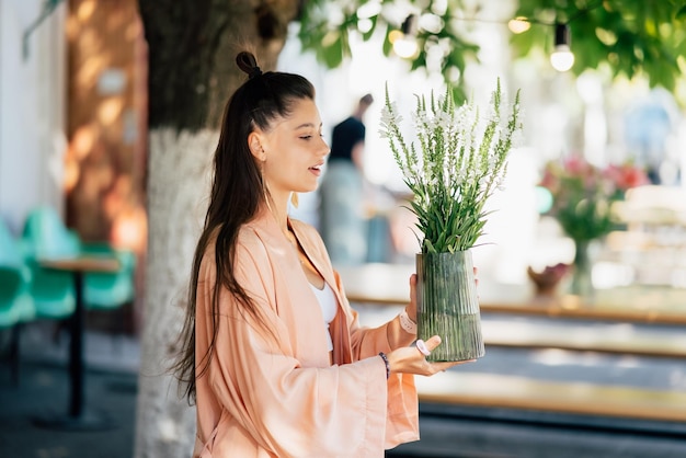 Femme tenir un vase de fleurs dans le café de la rue