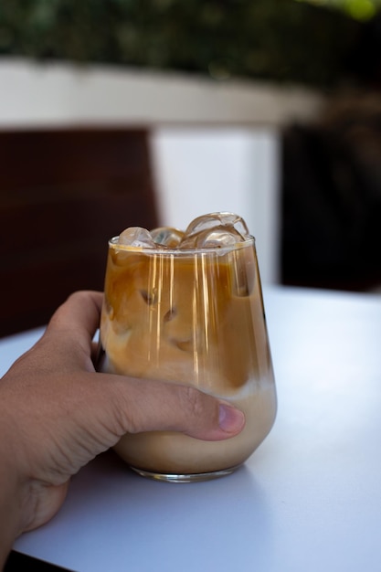 Femme tenir un verre de café glacé avec du lait à la crème