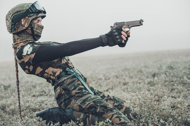 Femme en tenue militaire avec un pistolet dans ses mains