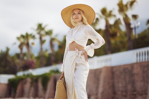 Femme en tenue de plage élégante à l'extérieur contre des palmiers en arrière-plan pendant l'été