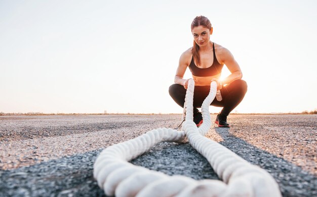 Femme en tenue de sport assise avec des nœuds sur la route le soir