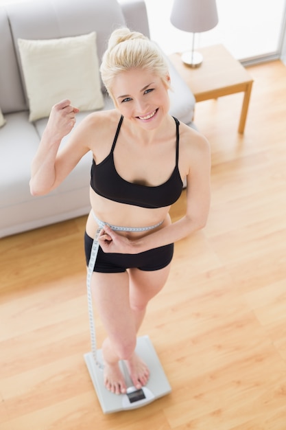 Femme en tenue de sport debout à l&#39;échelle tout en mesurant la taille