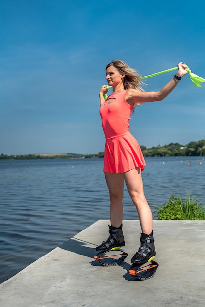 Femme en tenue de sport rose faisant de l'entraînement de sauts de kangoo