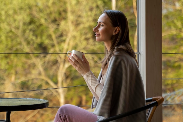 Femme sur la terrasse avec une tasse de café une femme avec un style de vie relaxant d'été à carreaux la vie rustique