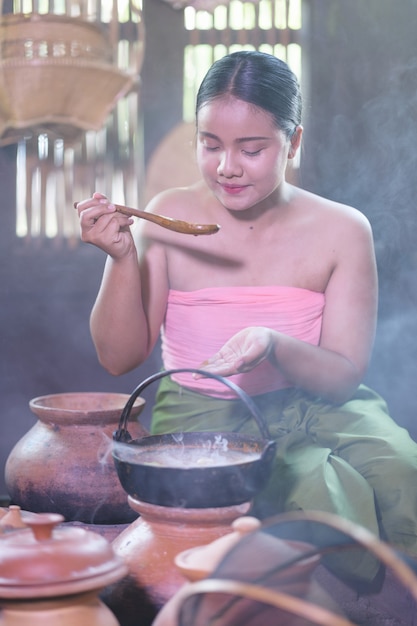 Femme thaïlandaise cuisine en robe thaï rétro