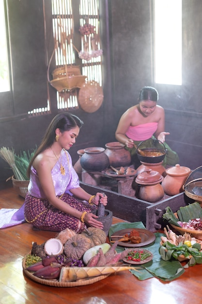 Femme thaïlandaise cuisine en robe thaï rétro