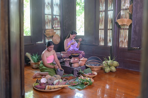 Femme thaïlandaise cuisine en robe thaï rétro