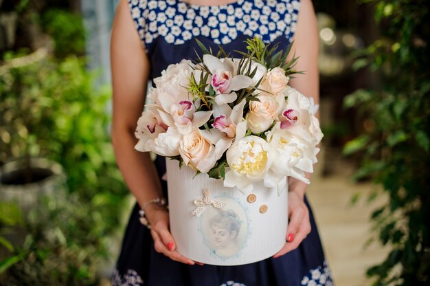 Femme tient une boîte avec une belle composition de fleurs