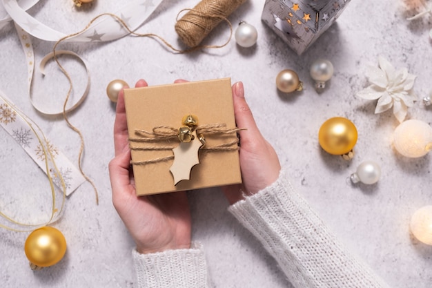 Une femme tient une boîte-cadeau décorée de ficelle et d'une étiquette en bois Préparation pour Noël et le Nouvel An
