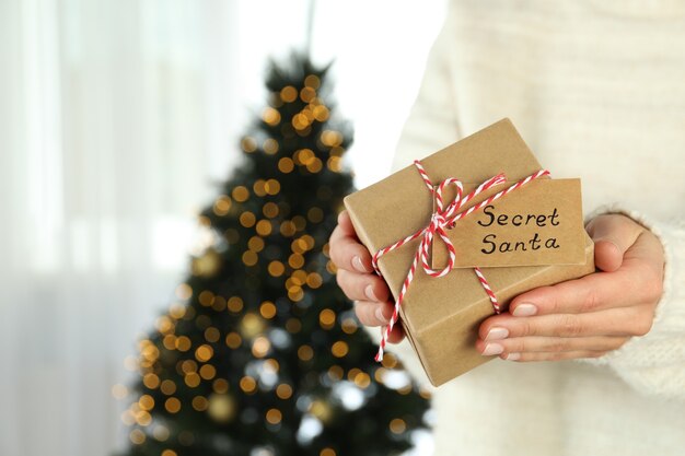 Une femme tient une boîte-cadeau Secret Santa, un espace pour le texte.