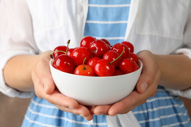 Femme tient un bol avec des cerises rouges fraîches