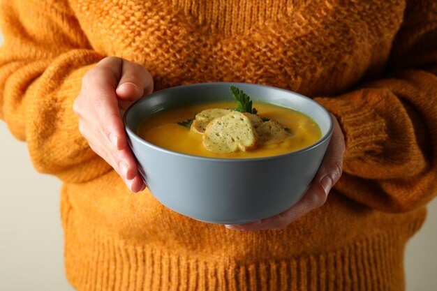 Femme tient un bol de soupe à la citrouille, gros plan