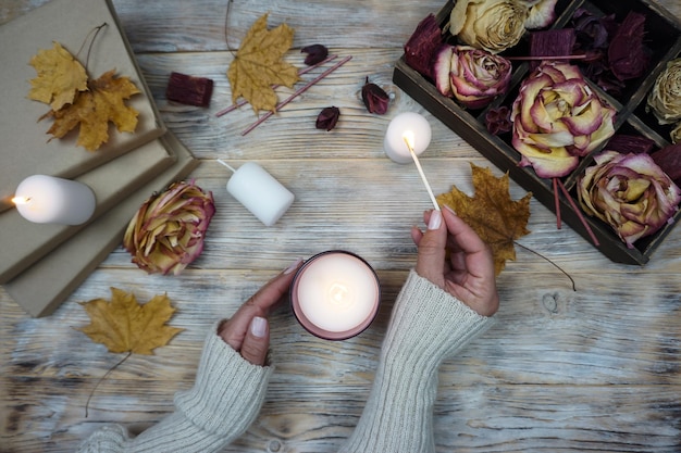 Une femme tient une bougie devant une boîte de feuilles d'automne.