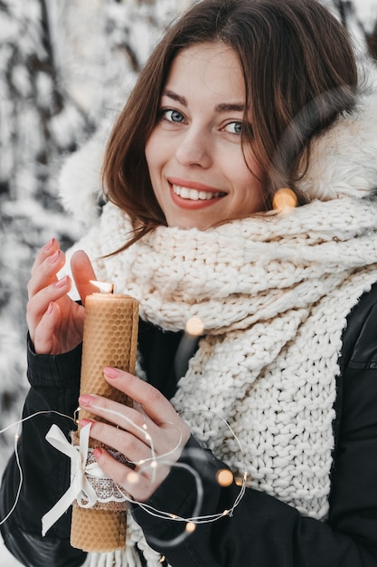 La femme tient une bougie et sourit.