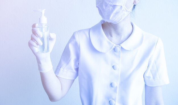 Une femme tient une bouteille de gel d'alcool dans sa main pour se nettoyer fréquemment les mains et prévenir l'infection à coronavirus, les premiers soins personnels pendant une crise épidémique. Concept d'auto-prévention et de soins de santé.