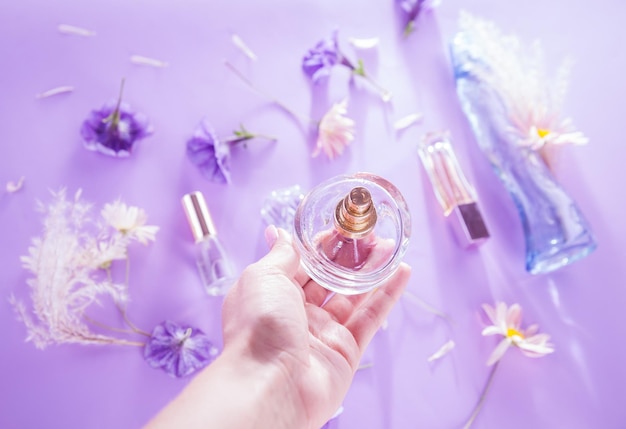 La femme tient une bouteille de parfum avec des fleurs