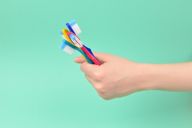 La femme tient des brosses à dents dans sa main sur un fond vert.