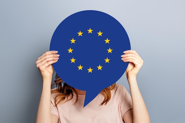 Femme tient une bulle blanche vierge avec le drapeau de l'union européenne isolé sur fond gris studio Concept de canal d'information de nouvelles