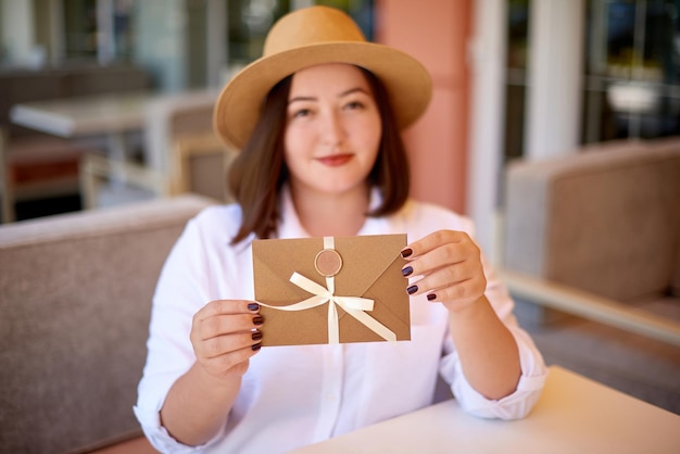 Une femme tient une carte-cadeau à présenter dans une carte de réduction de café pour les clients VIP pour faire du shopping ou voyager