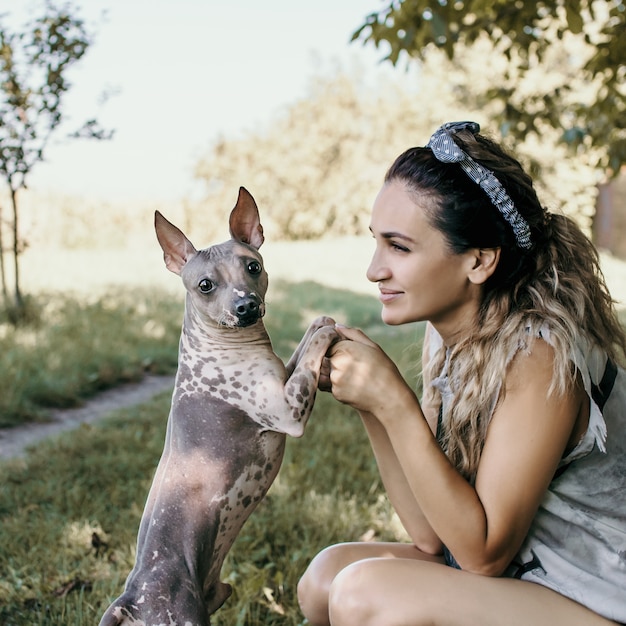 La femme tient le chien par les pattes sur un fond de parc