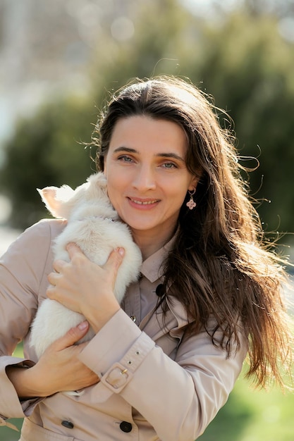 une femme tient un chiot blanc