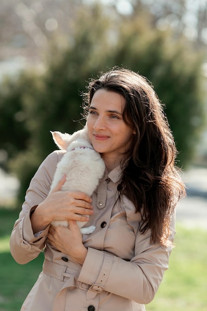 une femme tient un chiot blanc