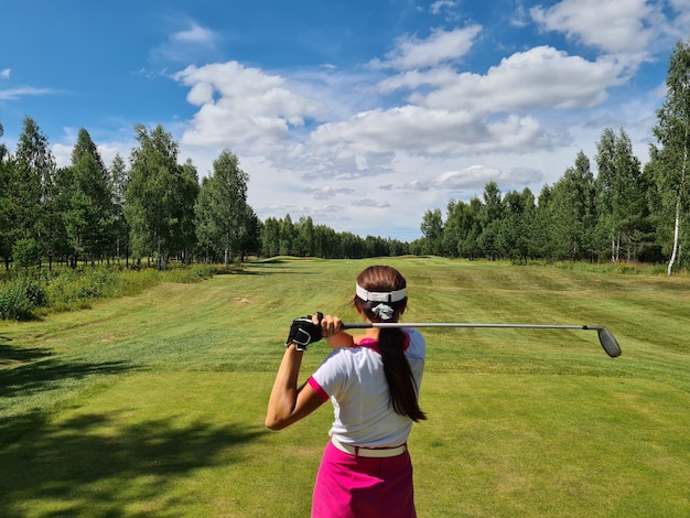 Une femme tient un club de golf derrière le dos en gros plan