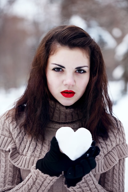 La femme tient un cœur de neige. Le concept de la Saint-Valentin