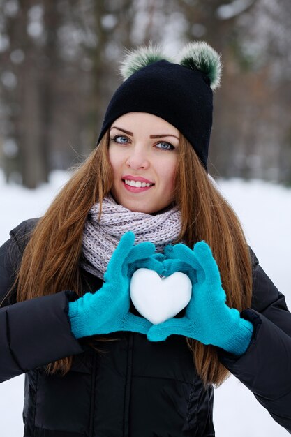 La femme tient un cœur de neige. Le concept de la Saint-Valentin