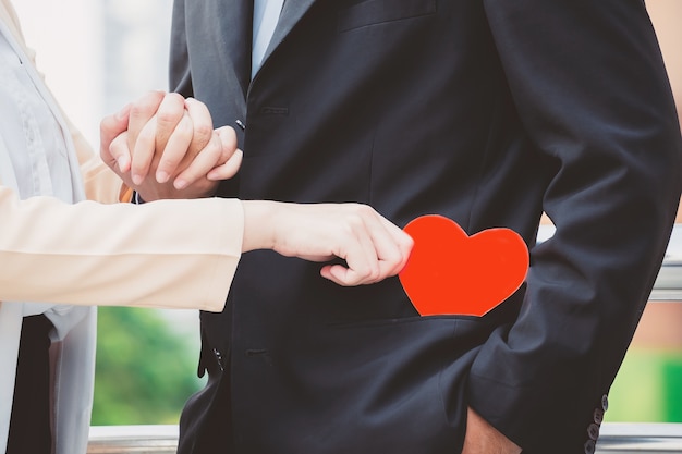 Une femme tient un coeur de papier rouge dans sa poche