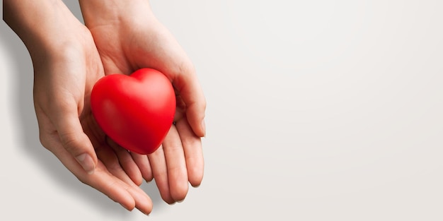 Une femme tient un coeur rouge dans ses mains.