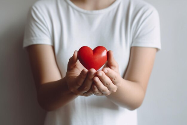 Une femme tient un coeur rouge dans ses mains.