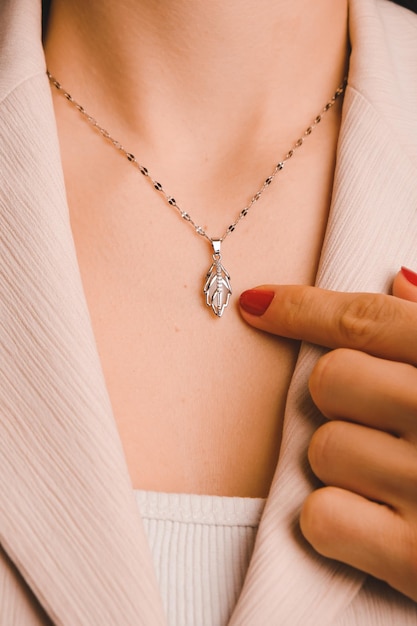 Une femme tient un collier avec un pendentif feuille.