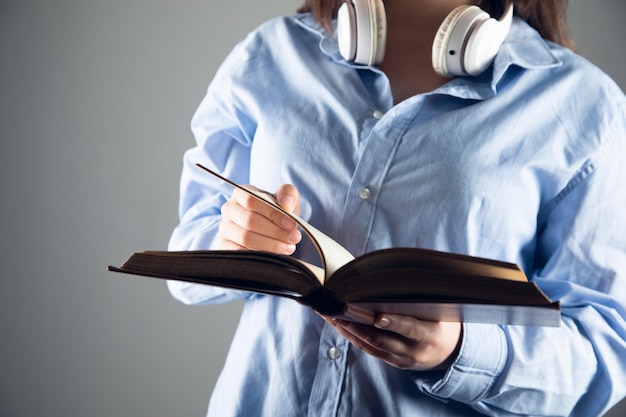 La femme tient le concept de livres audio de livre et d'écouteur