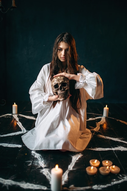 Femme tient le crâne humain dans la main, magie noire, sorcière