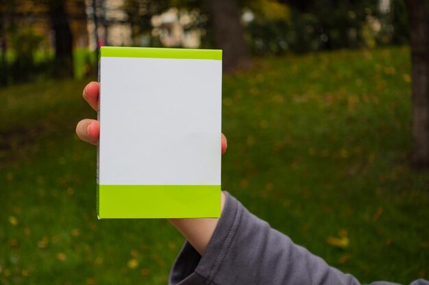 La femme tient dans la main une petite boîte en papier blanc et vert.