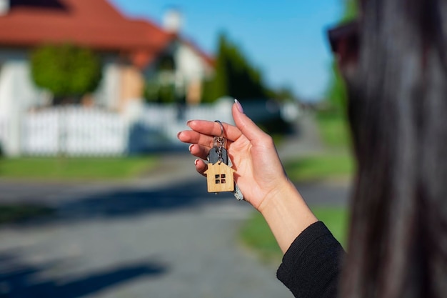 Une femme tient dans ses mains les clés de la maison sur fond de bâtiments résidentiels Concept d'achat et de location d'appartements