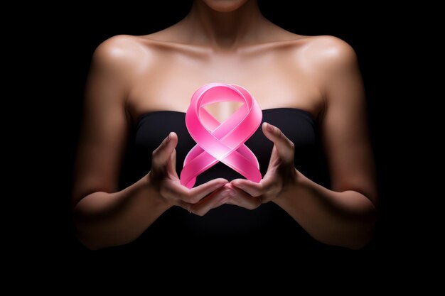 Une femme tient dans ses mains un ruban numérique rose, symbole contre le cancer.