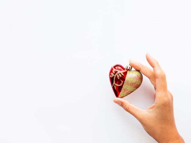 Femme tient la décoration du nouvel an - coeur rouge sur fond blanc