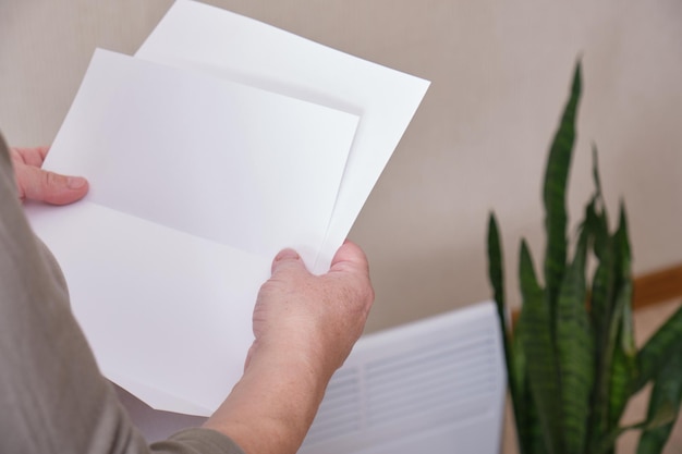 Une femme tient une feuille de papier dans ses mains, un radiateur électrique pour chauffer la maison, de grosses factures d'électricité