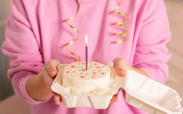 Une femme tient un gâteau bento avec une bougie dans ses mains des gâteaux de style coréen dans une boîte pour une personne