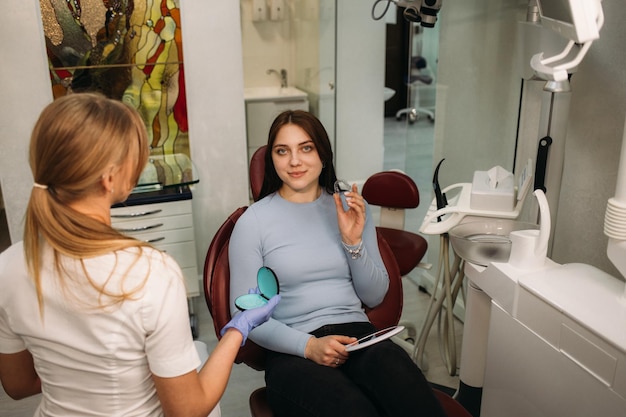 Une femme tient des gouttières en dentisterie alors qu'elle est assise dans un fauteuil dentaire