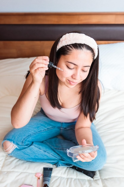 Une femme tient un liquide dans sa main et regarde son visage.