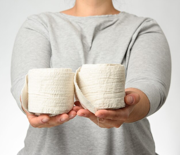 Femme tient en main un bandage élastique blanc pour le corps, fond gris