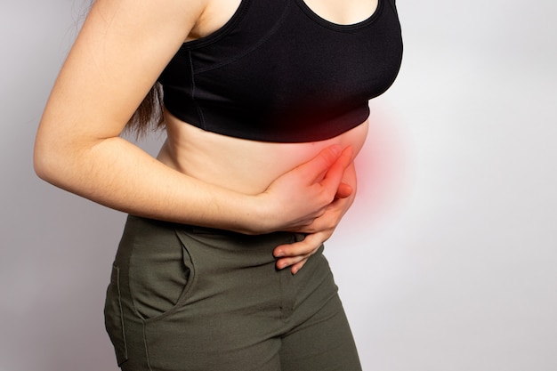 Une femme tient les mains sur un estomac malade avec un ulcère ou une gastrite.