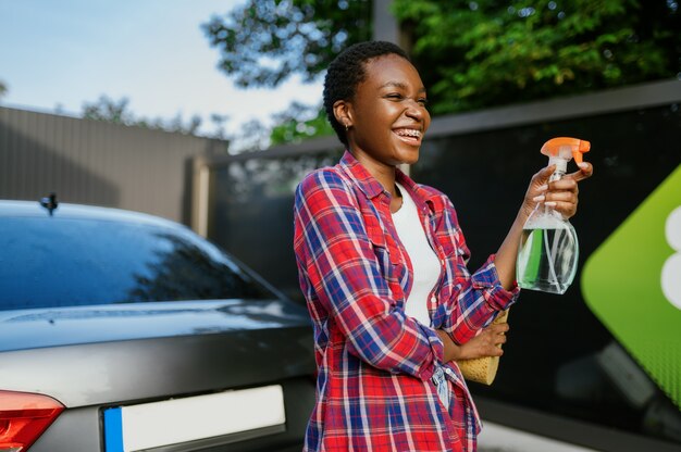 Une Femme Tient Un Nettoyant Pour Vitres, Une Station De Lavage De Voiture à La Main