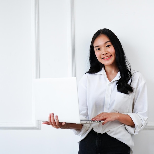 Photo une femme tient un ordinateur portable et sourit.