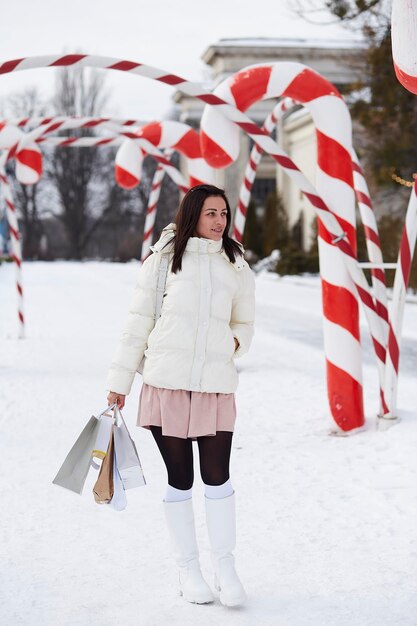 Une femme tient des paquets-cadeaux après avoir fait du shopping en plein air parmi les décorations de Noël