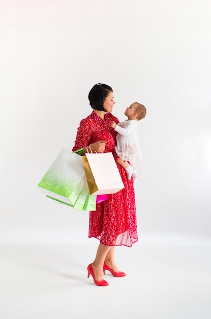 La femme tient des paquets. Maman et petit enfant font du shopping. Fond blanc. Vendredi noir.