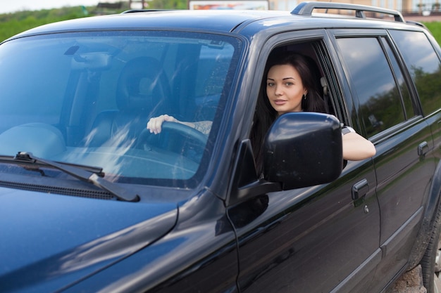 La femme tient une roue de voiture noire avec une main tatouée.